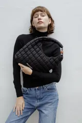 Cartera tipo hobo de Rotunda, color negro, con diseño acolchado en cuadrados y detalle de eslabón plástico en la manija. Incluye parche con el logo de la marca en el frente.