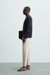 Pantalón chino de corte slim fit, confeccionado en tejido elástico. Presenta bolsillos frontales, bolsillos traseros de vivo con botón y cierre frontal con cremallera y botón.