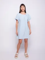Vestido corto de corte holgado, color celeste, con cuello redondo fruncido y mangas cortas. Está confeccionado en una tela con textura diferenciada que le aporta relieve.