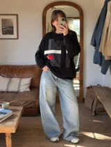 Buzo negro de corte oversize con cuello redondo, confeccionado de forma artesanal. Cuenta con un diseño geométrico frontal tipo collage en tonos grises, blanco y un detalle en rojo.