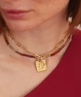 Collar de plata con cadena de eslabones alargados y dije de medalla rectangular con textura rústica, grabado en relieve con forma de estrella y una piedra brillante incrustada en el centro.