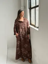 Vestido largo marrón de lino con estampado floral, cuello redondo holgado y mangas tres cuartos.