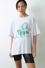 Remera de algodón gris melange con corte oversize, manga corta y estampa localizada en el frente con motivos deportivos en tonos verde y rosado.