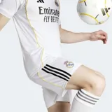 Short de fútbol Adidas Real Madrid, modelo local temporada 25/26, color blanco con tres franjas negras en el lateral y escudo del equipo bordado.