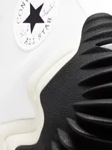 Championes de caña alta Converse con diseño de plataforma ondulada. Presentan una parte superior de lona de algodón orgánico, con el icónico parche de estrella en el lateral. La entresuela es de espuma CX para mayor comodidad, con una suela dentada de goma en colores contrastantes negro y marrón.