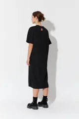 Vestido largo de manga corta y corte oversize, confeccionado en tejido con textura. Presenta cuello redondo y un parche decorativo en la parte posterior.
