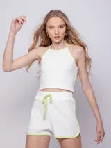 Short de tejido de punto con diseño de pequeños calados, color blanco con ribetes en verde lima. Posee cintura elástica con cordón ajustable y terminaciones redondeadas.