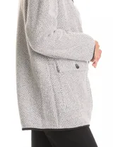 Cardigan de tejido de punto con diseño de espiga en color beige, totalmente forrado en corderito sintético blanco. Presenta cuello solapa, cierre frontal con botones, bolsillos tipo parche con solapa y terminaciones con vivos en contraste.