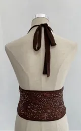 Top marrón con lentejuelas y espalda descubierta, con cuello halter y escote en V pronunciado.