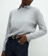 Suéter de punto gris con cuello redondo y diseño de cuello camisero celeste superpuesto. Presenta mangas largas y terminaciones acanaladas en puños y cintura.