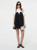 Vestido corto negro, estilo globo o balloon, con escote corazón pronunciado. Se lleva sobre una remera blanca de manga corta.