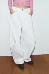 Jeans blancos de tiro medio con cinco bolsillos, detalle de costuras torcidas y cierre frontal con cremallera y botón metálico.