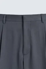 Pantalón de traje con corte flare fit, confeccionado en tejido con lana. Presenta diseño de tiro medio con pinzas frontales, bolsillos laterales y bolsillos traseros de vivo. Cierre frontal con cremallera y botón.