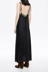 Vestido largo negro con caída fluida, escote en V con tirantes finos y detalles de encaje floral en el escote y el pecho.