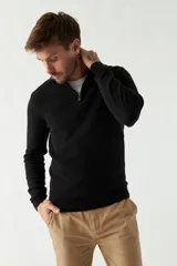 Sweater de punto negro con cuello alto y cierre parcial con cremallera.