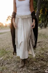 Cinturón artesanal de cuero color arena, con flecos largos y hebilla cuadrada metálica.