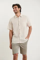 Camisa sport de manga corta, confeccionada en una mezcla de lino y algodón. Presenta cuello clásico, cierre frontal con botones de coco y un bolsillo aplicado en el pecho.