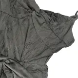 Vestido corto negro de corte asimétrico con escote en V y tirantes finos. Presenta un diseño con efecto desgastado y una sobrefalda con lazo frontal que aporta volumen y movimiento.