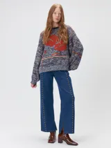 Sweater de punto con diseño geométrico y gráfico frontal en color rojo. Presenta cuello redondo, mangas largas holgadas y un ajuste suelto.