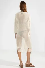 Cárdigan largo color crema de punto abierto con flecos en el ruedo y lazo de ajuste en el escote.