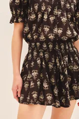 Short de voile de algodón con estampado floral en tonos beige sobre fondo negro. Presenta un diseño de corte amplio con cintura elástica y lazo ajustable para un calce cómodo.