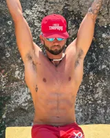 Gorra de béisbol de cinco paneles sin estructura color rojo, con visera plana y bordado frontal en tono crudo con la frase 'I NEED Therapy'. Presenta detalles bordados adicionales y correa ajustable de nailon en la parte trasera.