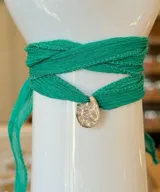 Gargantilla de cinta de seda natural color verde, con dije central de plata 950 de forma irregular y textura orgánica, con un cristal engastado en el centro.