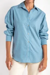 Camisa celeste con rayas verticales blancas, de corte oversize y manga larga.