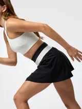 Falda pantalón deportiva de color negro con pretina ancha tejida en franjas blanca y negra, diseño plisado al frente y shorts internos.
