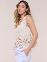 Top de crochet color beige, confeccionado en hilo de algodón con diseño calado de rosetones, escote redondo y silueta holgada sin mangas.