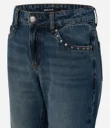 Pantalón de jean azul con lavado desgastado, de corte bootcut, tiro bajo y bolsillos funcionales con tachas metálicas.