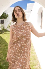 Vestido midi sin mangas, color marrón con estampado floral en blanco, con tajos laterales y cierre con botón en la espalda.