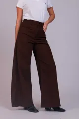Pantalón de corte wide leg confeccionado en pana acanalada color marrón chocolate. Presenta tiro alto, cierre frontal con botón y bolsillos laterales.