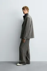 Pantalón de vestir con corte flare y ajuste relajado, confeccionado en tejido con viscosa y patrón de espiga. Cuenta con bolsillos frontales, bolsillos traseros de vivo y cierre frontal con cremallera y botón.