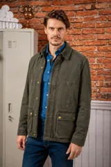 Campera encerada de estilo clásico con cuello de pana, cierre frontal con cremallera y botones a presión, y bolsillos frontales de gran capacidad.