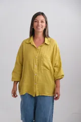 Camisa oversize de lino italiano color mostaza, con cuello camisero, cierre frontal de botones, bolsillo en el pecho y mangas largas con puños elásticos.