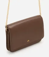 Cartera bandolera de poliuretano color marrón, de tamaño pequeño, con solapa y detalle de logo dorado en la parte inferior. Cuenta con correa larga de cadena metálica dorada.