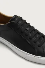Zapatilla de estilo minimalista con cordones, confeccionada en material sintético de acabado mate. Presenta una horma redonda, forro interior en tono contrastante y suela de goma con textura ligera.
