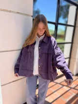 Campera corta de pana color violeta con cuello camisero, cierre frontal con botones dorados, bolsillos de parche en el pecho y corte recto.