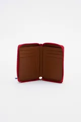 Billetera chica de cuero color rojo con cierre de cremallera y tirador celeste. Tiene bolsillo trasero y abertura al medio.