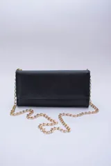 Cartera tipo sobre color beige con textura granulada y correa de cadena dorada.