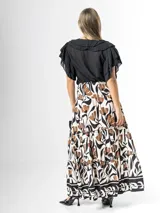 Falda larga de viscosa con cintura elástica fruncida tipo smock y diseño de volantes escalonados. Presenta un estampado botánico en tonos beige, marrón y negro sobre fondo blanco.