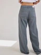 Pantalón de tiro medio alto, color beige, con bolsillos delanteros y traseros. Presenta detalles de atraques y triples costuras en color amarillo. Confeccionado en una mezcla de lino, algodón y viscosa.