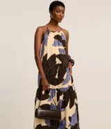 Vestido midi evasé de viscosa color beige con estampa de follaje en tonos marrones y celestes, diseño de frente única con tirantes finos.