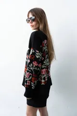 Buzo tejido de algodón negro con diseño jacquard de flores multicolor, cuello en V y mangas largas.