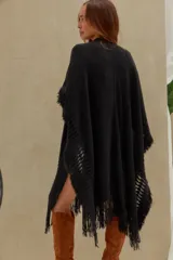 Poncho negro de punto con detalles calados y terminaciones de flecos en los bordes.