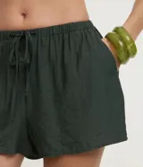 Short de playa color beige, confeccionado en viscosa y poliamida, con diseño holgado, bolsillos laterales, cintura elástica con cordón de ajuste tipo lazo y detalle de botones frontales.