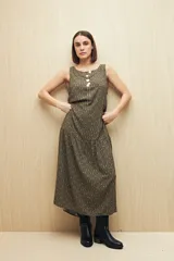 Vestido largo sin mangas, color verde oscuro con estampado geométrico en beige. Tiene escote redondo y corte con volado en el ruedo.