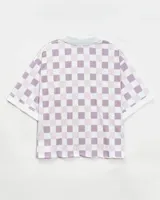 Camiseta tipo polo de estilo deportivo, con diseño a cuadros en tonos blanco y lila. Presenta cuello polo, mangas cortas y estampa gráfica circular en el frente con la inscripción 'anm'.