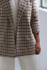 Blazer de corte recto con estampado a cuadros en tonos beige y marrón, con solapas clásicas y cierre frontal.